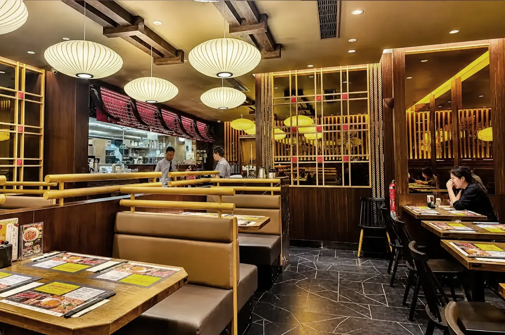 Le Shrimp Ramen restaurant interior featuring wooden booth seating, paper lantern lights, lattice partitions, and diners at tables