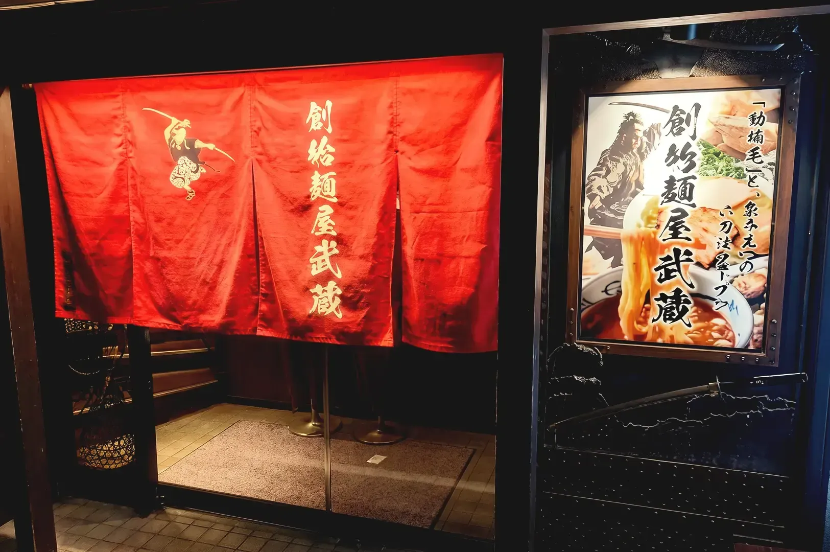 Large red banner with japanese illustration and letters beside a ramen poster with black japanese letters