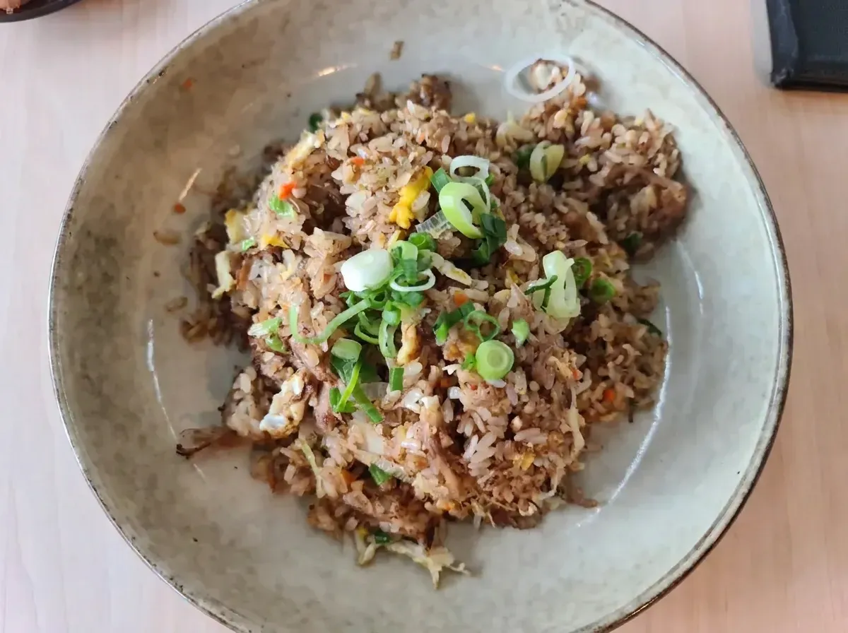 Overhead view of a plate of Japanese fried rice garnished with chopped green onions.