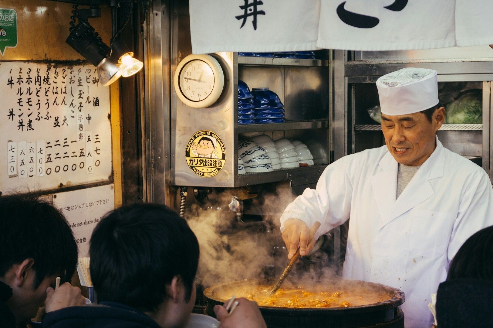 A ramen chef skillfully cooking noodles and broth in a bustling restaurant kitchen.