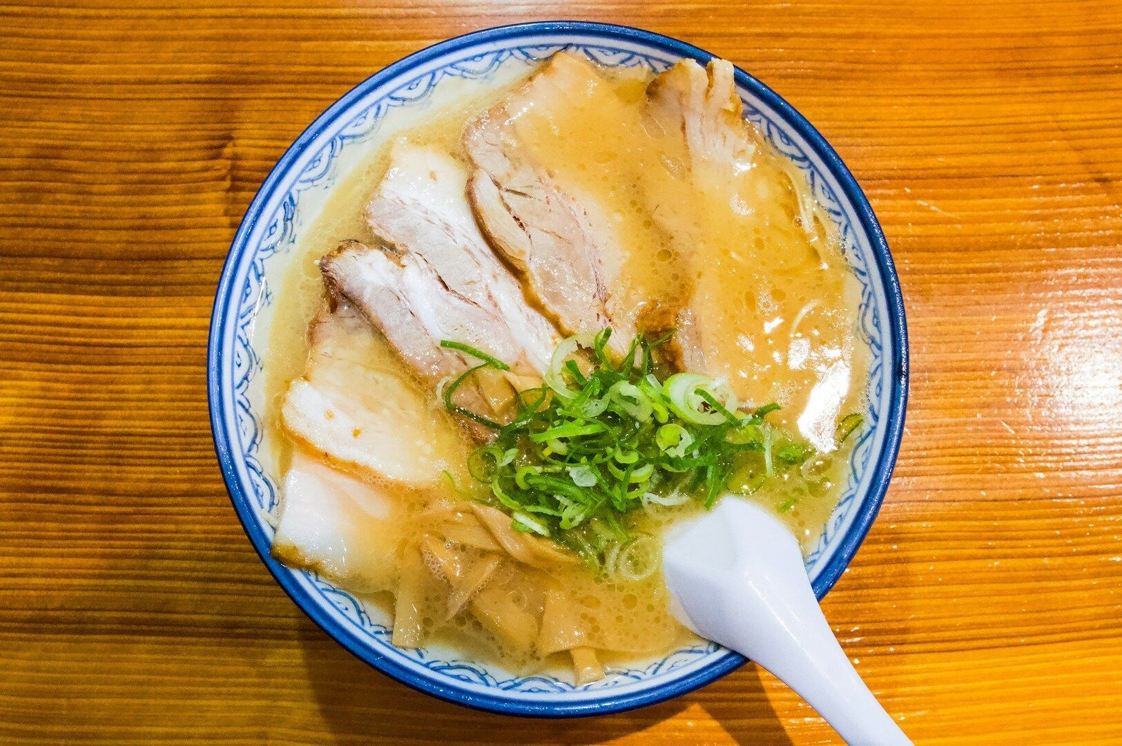 A bowl of Tonkotsu Ramen featuring rich broth, tender meat, and garnished with fresh green onions.