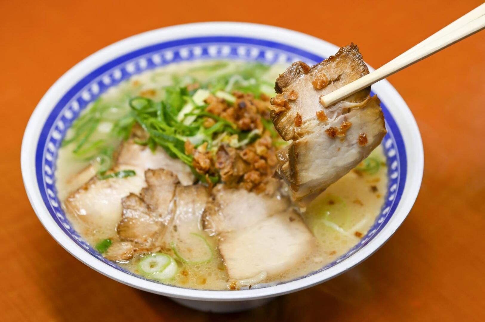 A bowl of Tonkotsu Ramen featuring Kagoshima Kurobuta, topped with meat and fresh vegetables.