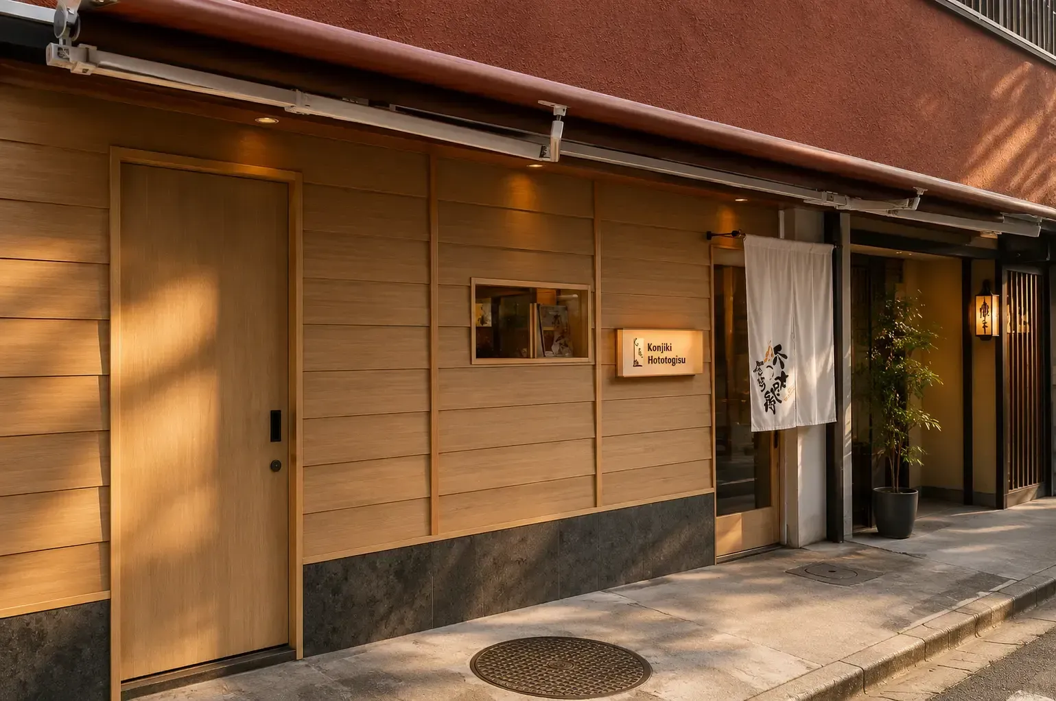 Clean, minimalist wooden facade and entrance of the Konjiki Hototogisu restaurant on a street.
