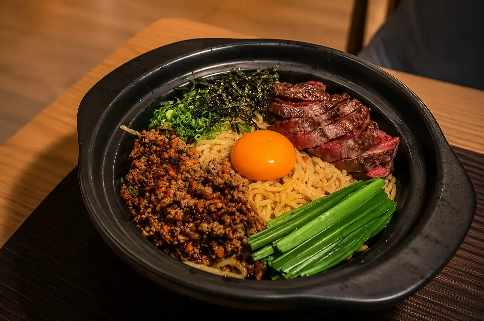 Hot pot ramen topped with sliced grilled wagyu beef, minced meat, chives, and a raw egg yolk.
