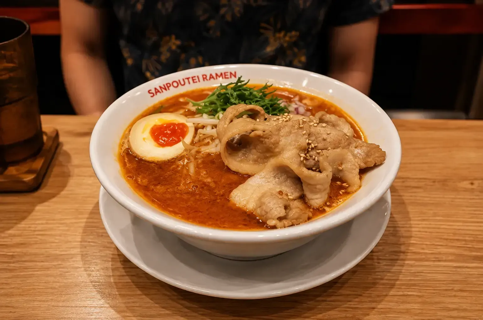 Creamy, reddish spicy ramen broth topped with thin sliced pork belly, a soft-boiled egg half.