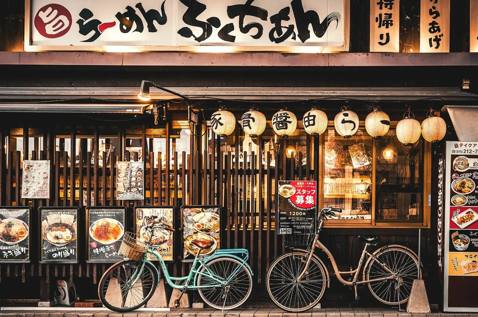 Japanese ramen shop with displayed menu posters and two bicycles in front