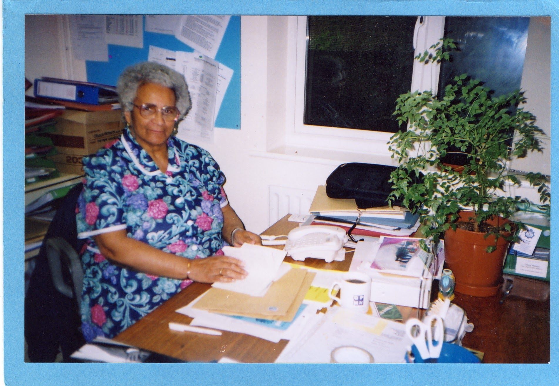 Faith Matyszak-Gander sitting at a desk with papers and community records around her.