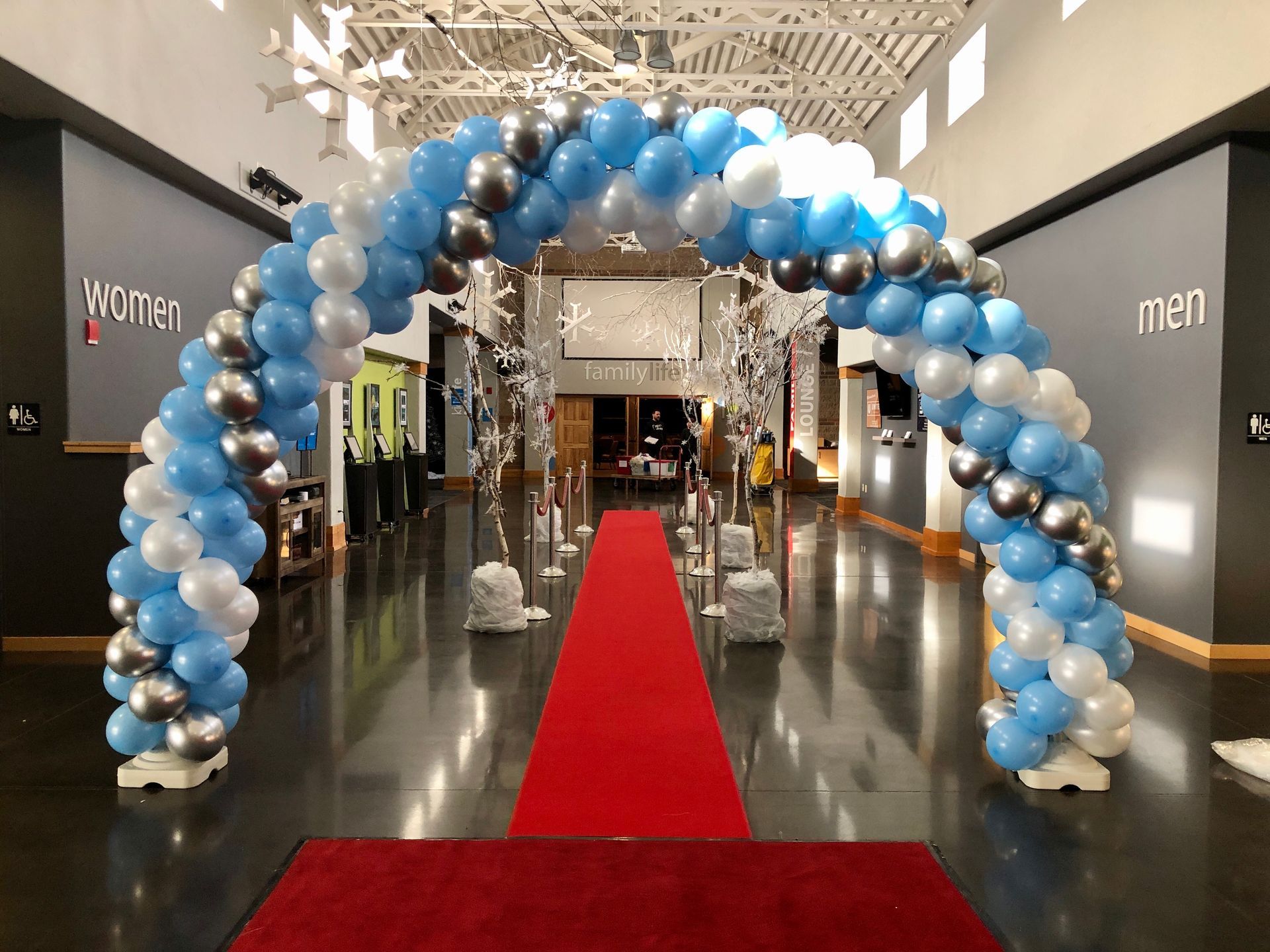 A large room with a red carpet and a balloon arch.