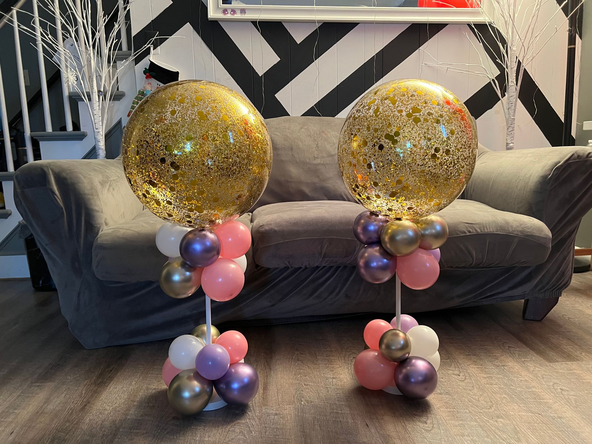 Two balloons are sitting on top of a couch in a living room.