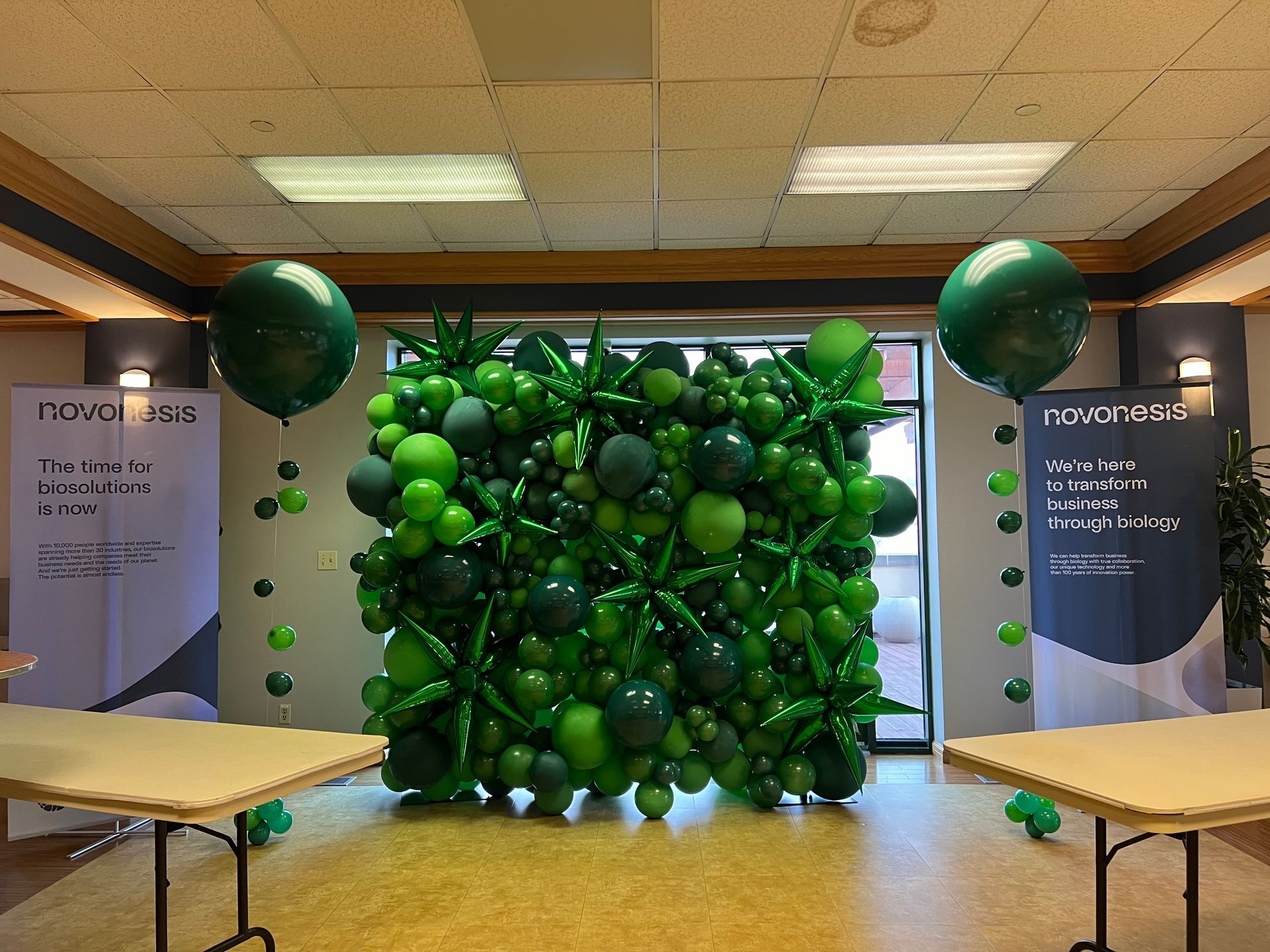 A room filled with green balloons and tables.