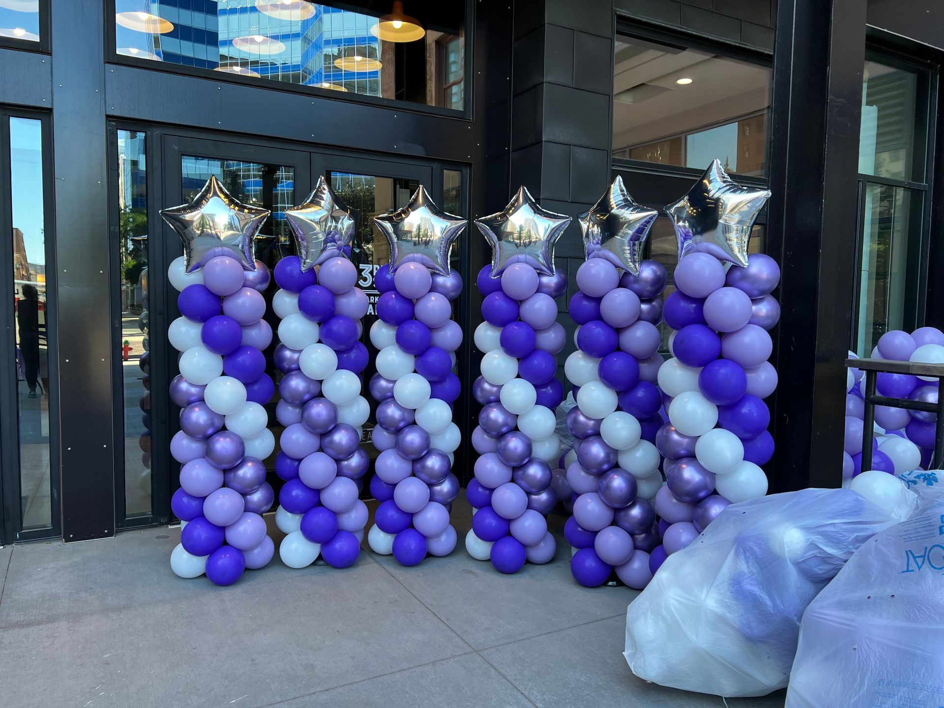 A row of purple and white balloons are lined up in front of a building.