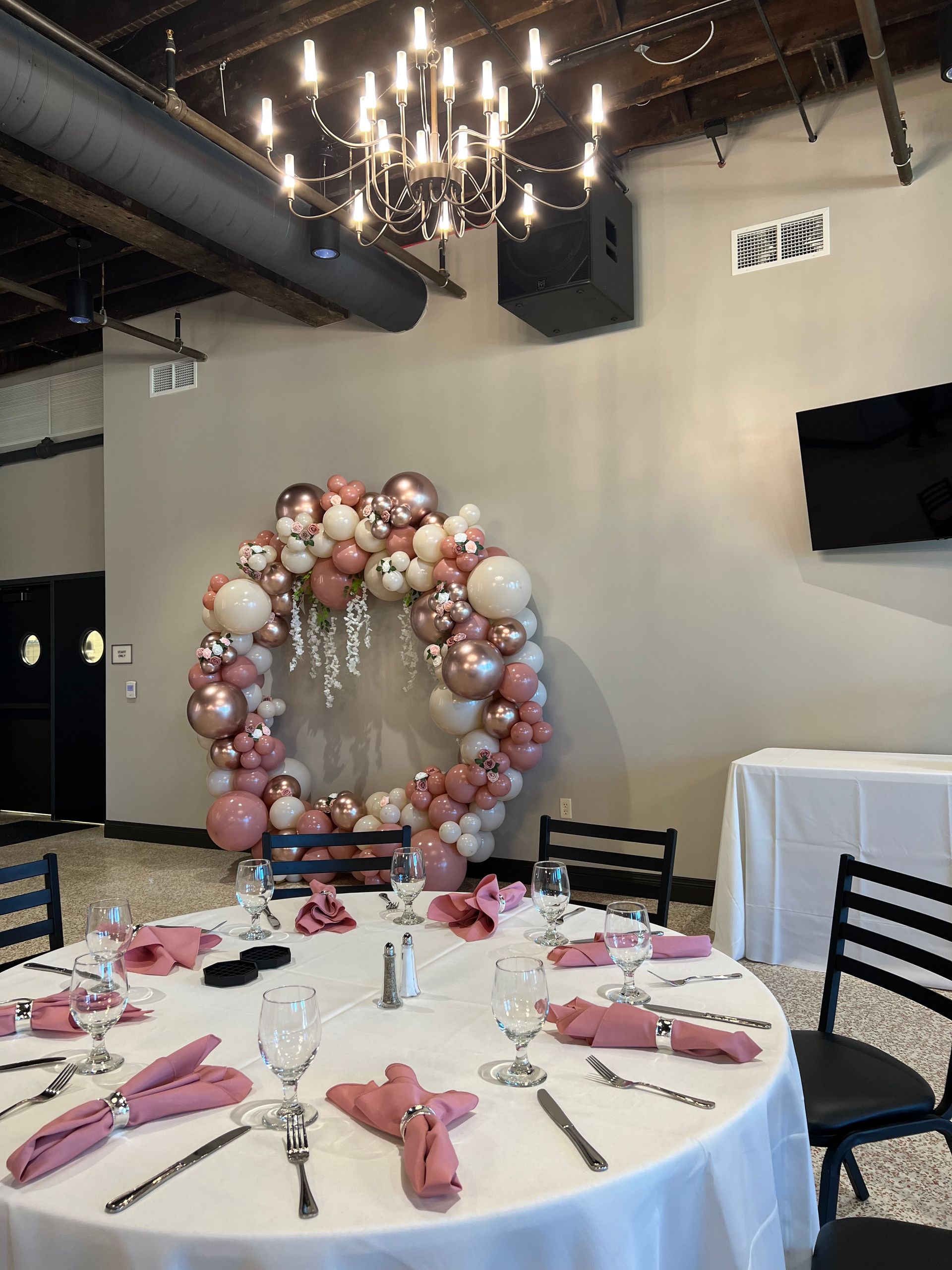 A room with a table and chairs and a wreath of balloons on the wall.