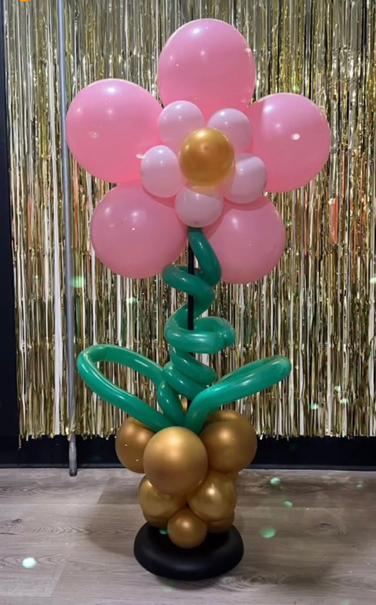A flower made out of pink and gold balloons on a stand.
