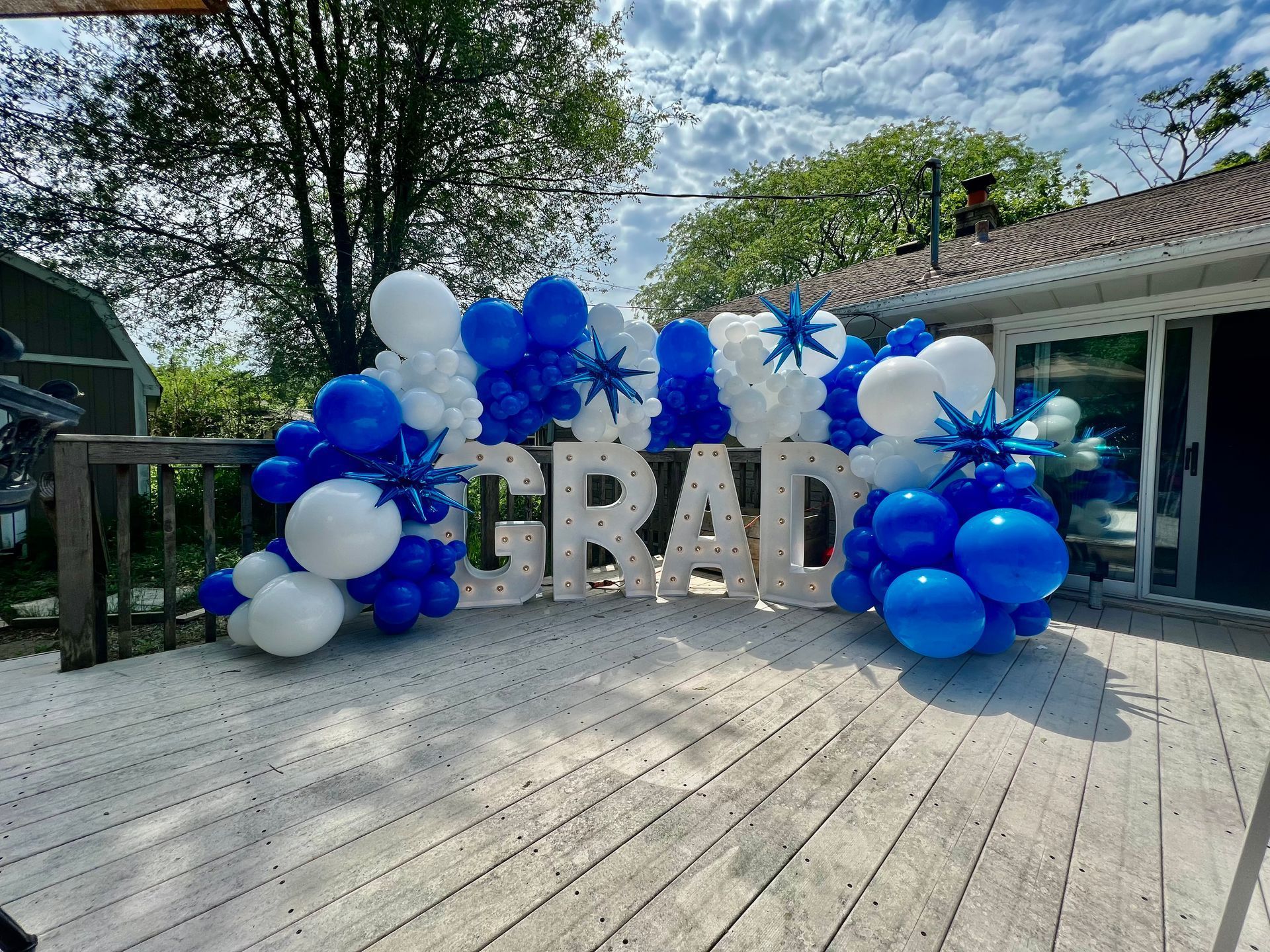 A wooden deck decorated with blue and white balloons and a sign that says `` grad ''.