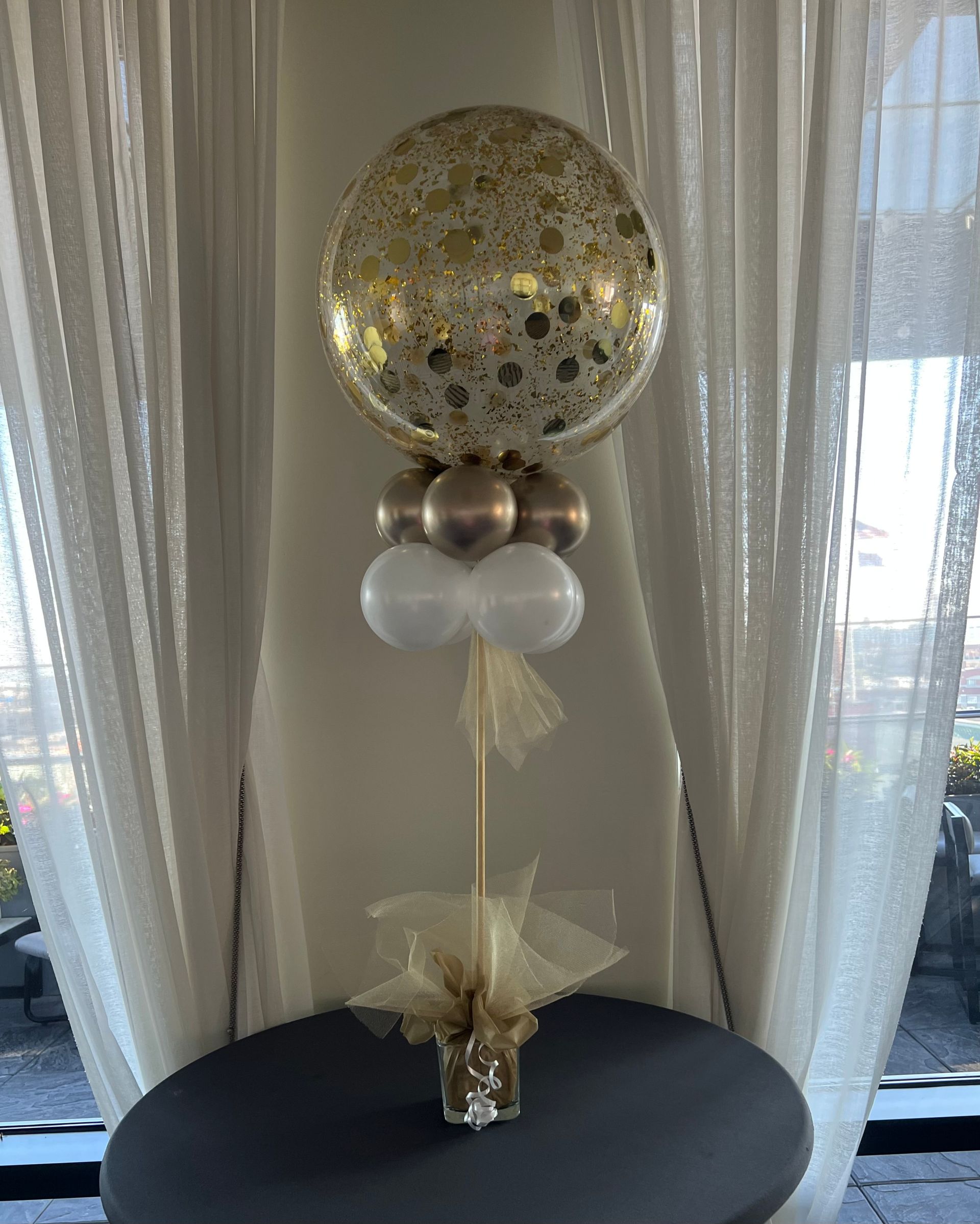 A table topped with balloons and a confetti balloon on a stick.