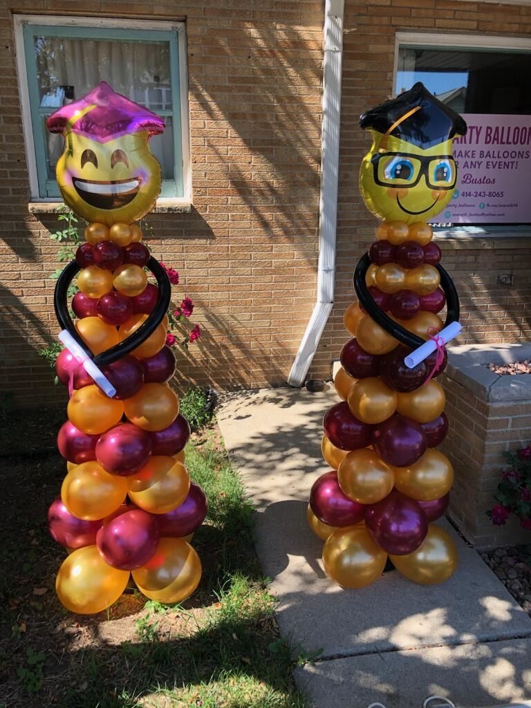 A couple of balloons standing next to each other in front of a brick building.