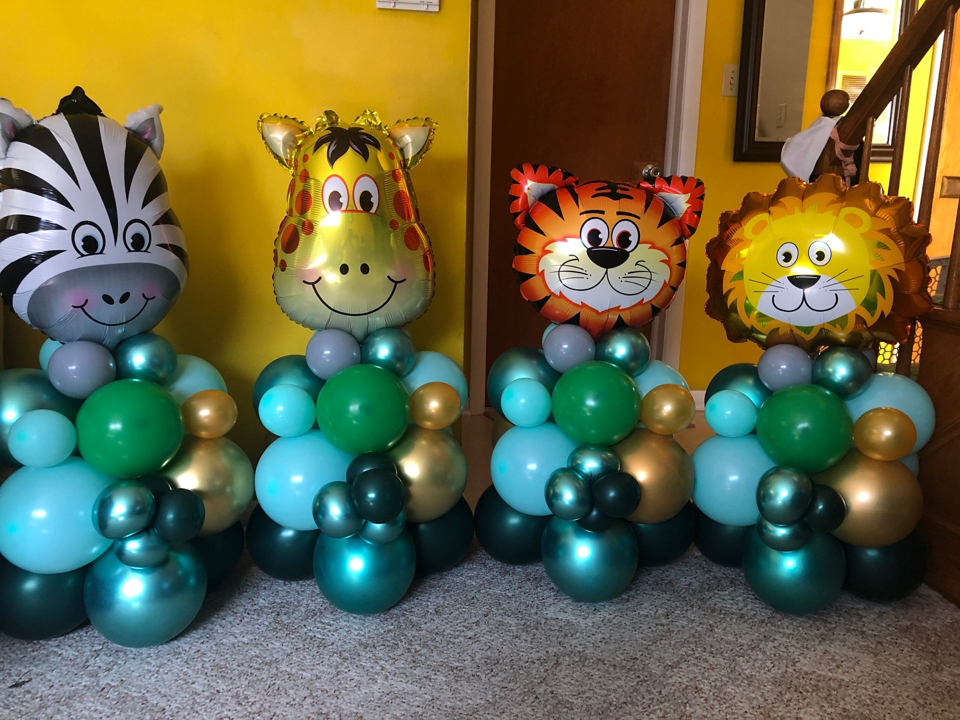 A zebra , a giraffe , and a lion are sitting on top of balloons.