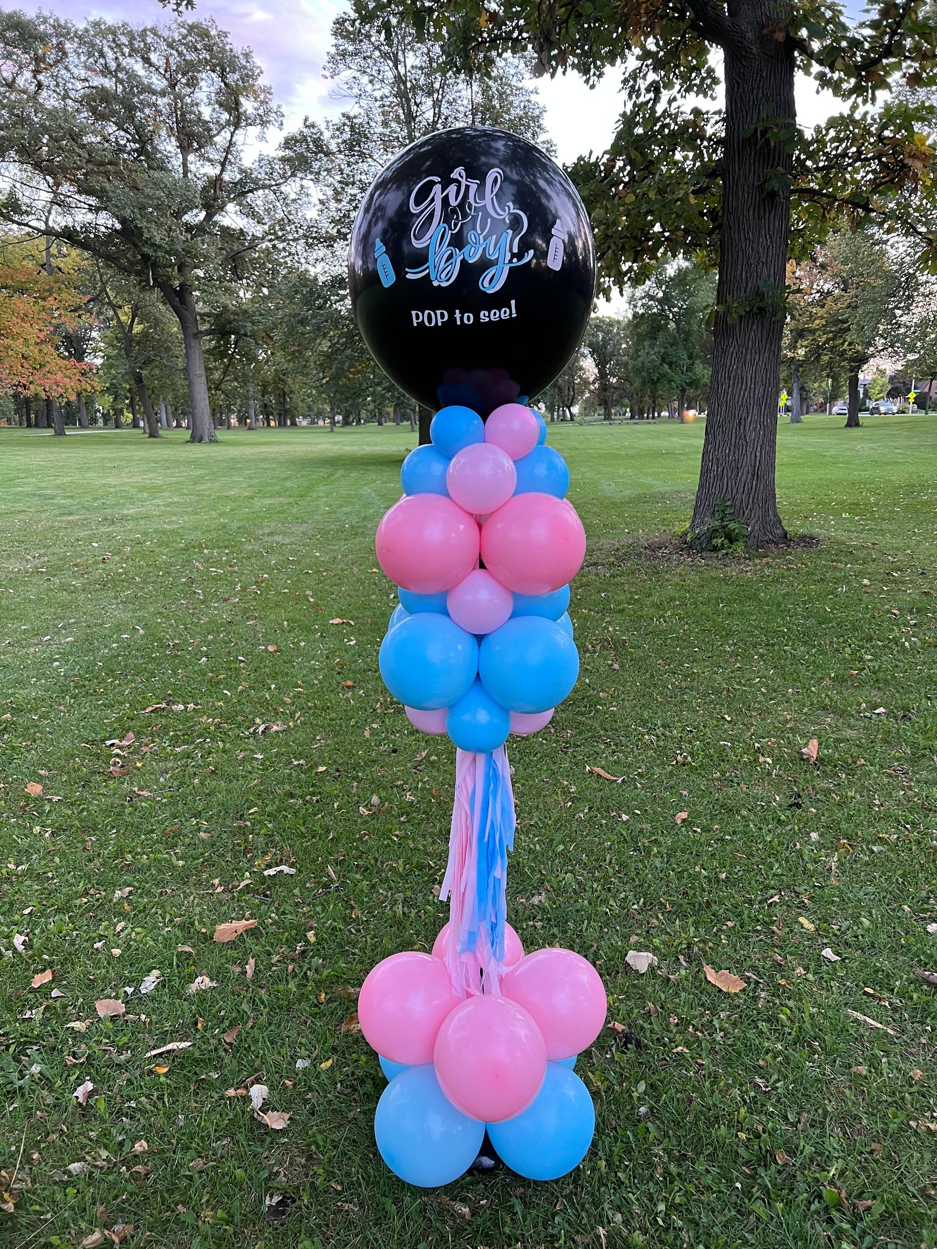 A bunch of balloons are sitting on top of a pole in a park.