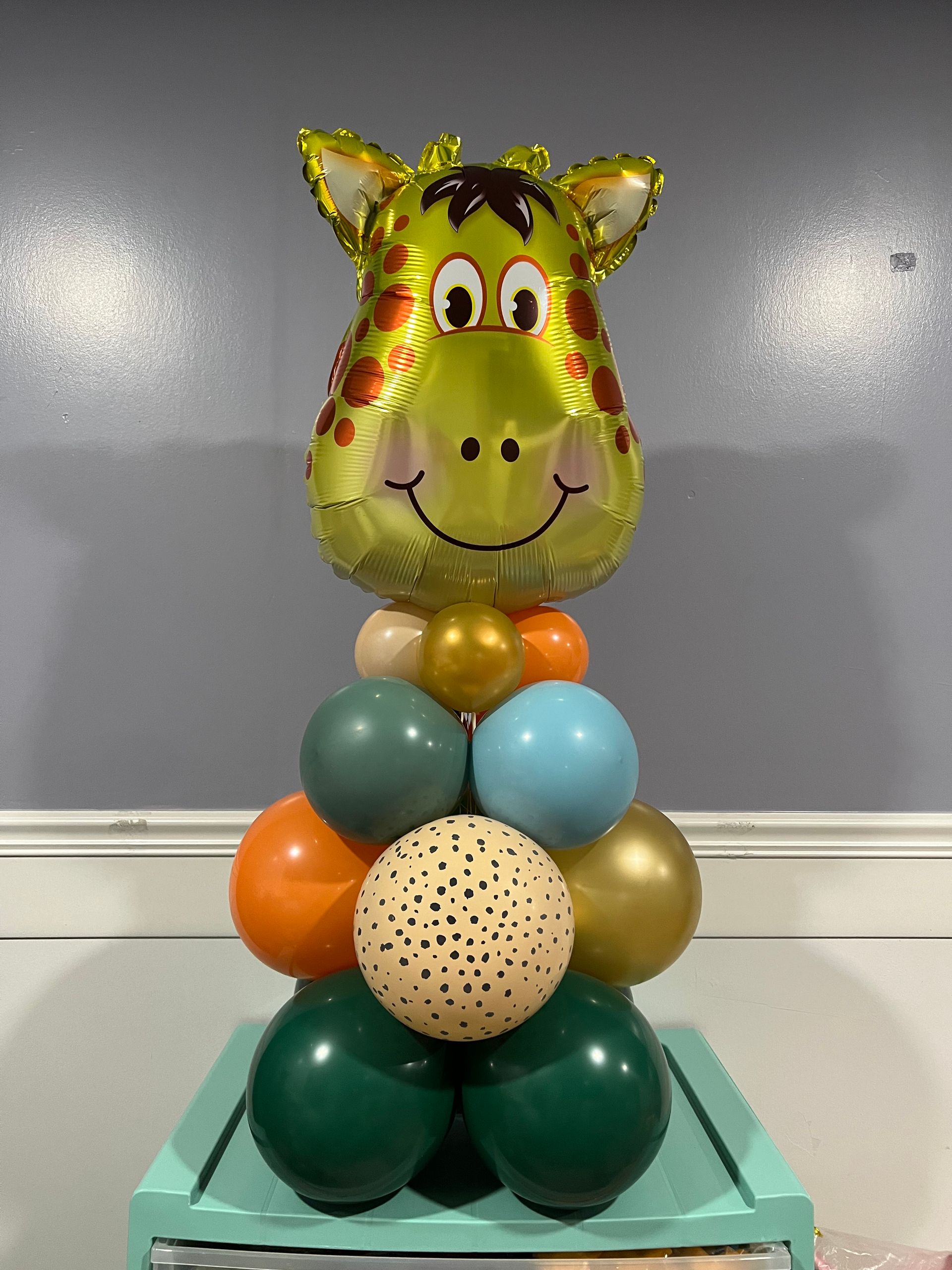 A giraffe balloon is sitting on top of a stack of balloons.