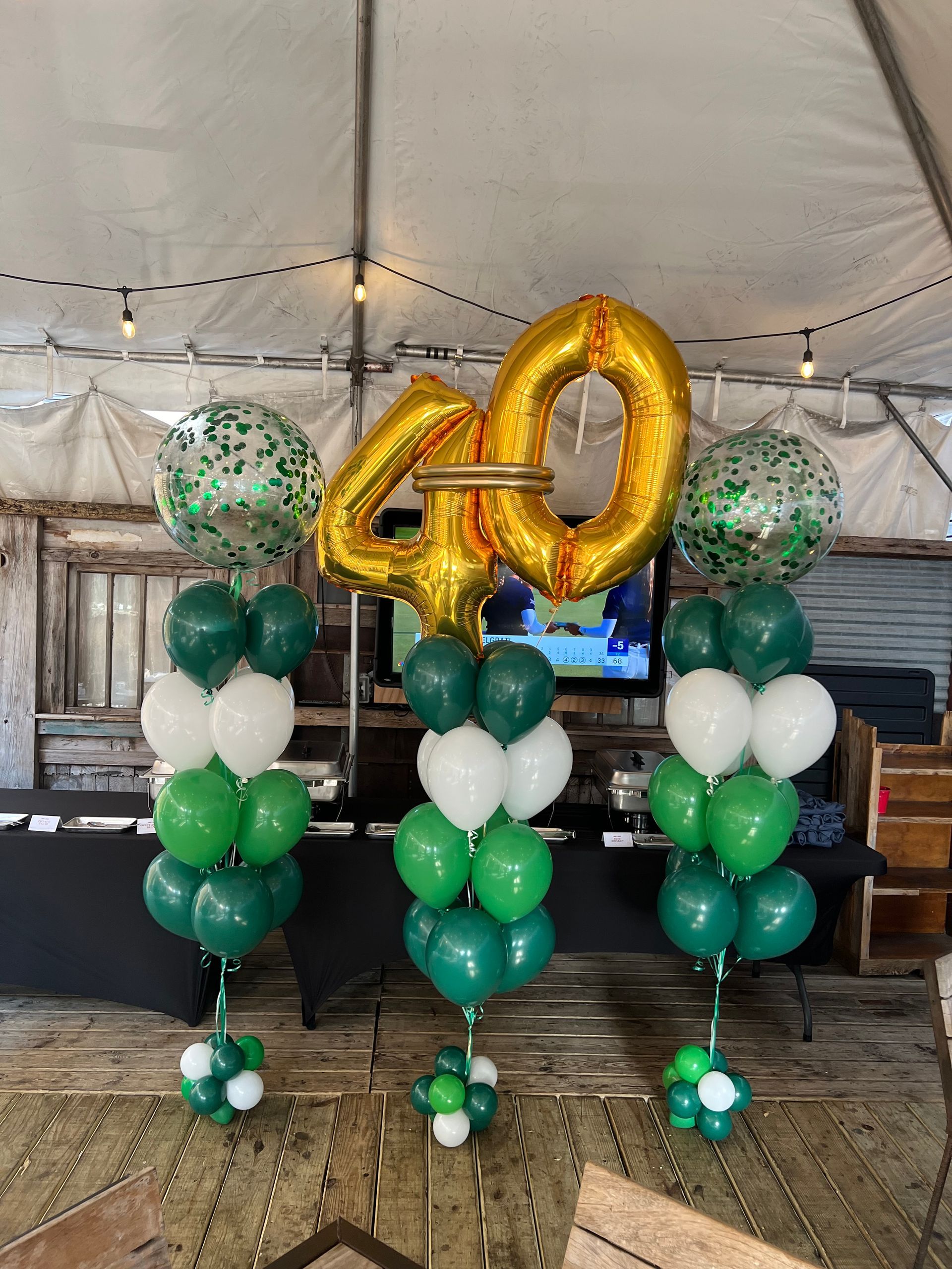 A bunch of green and white balloons with a gold number 40 on top of them.