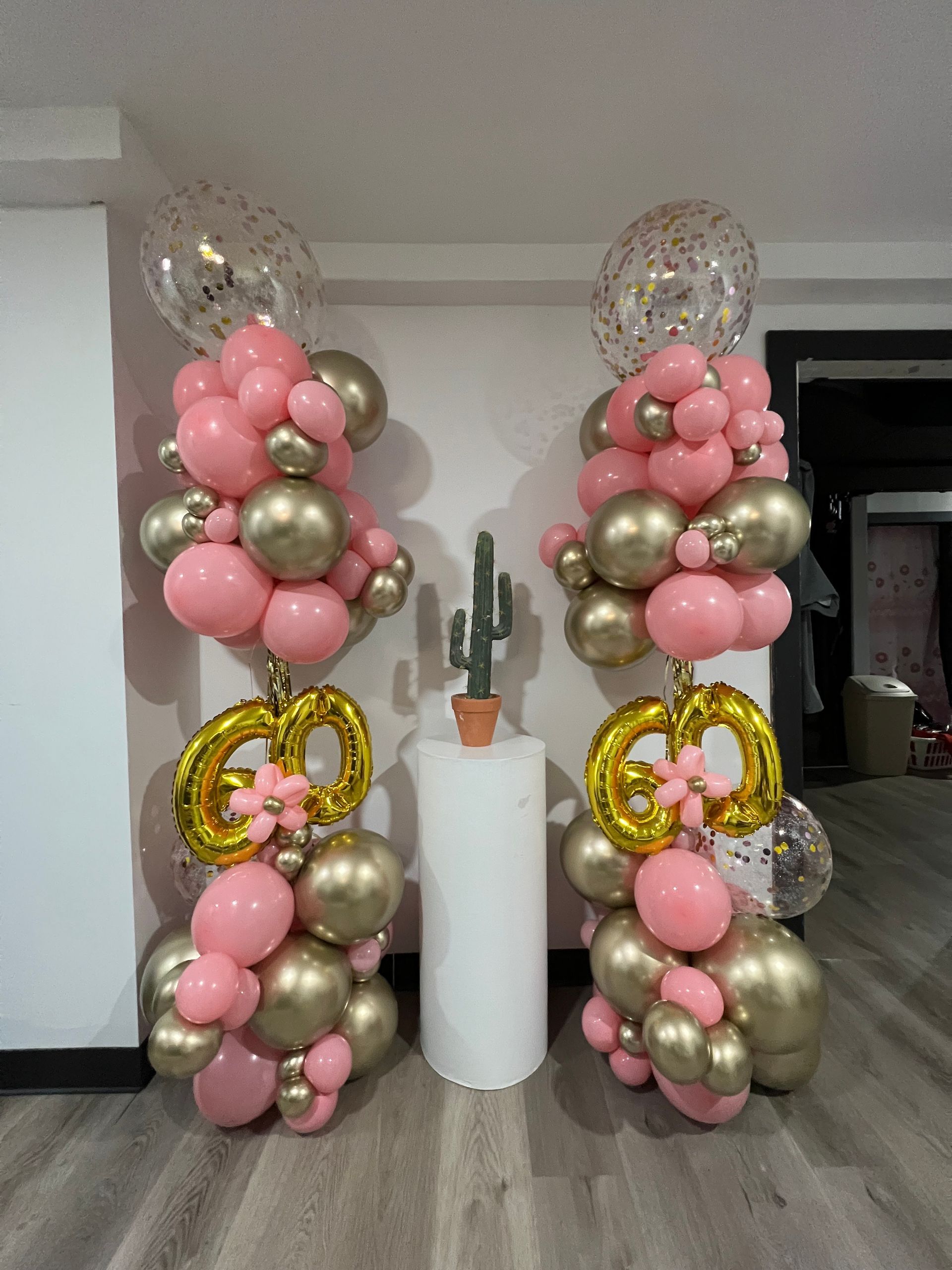 Two columns of pink and gold balloons are sitting next to each other in a room.