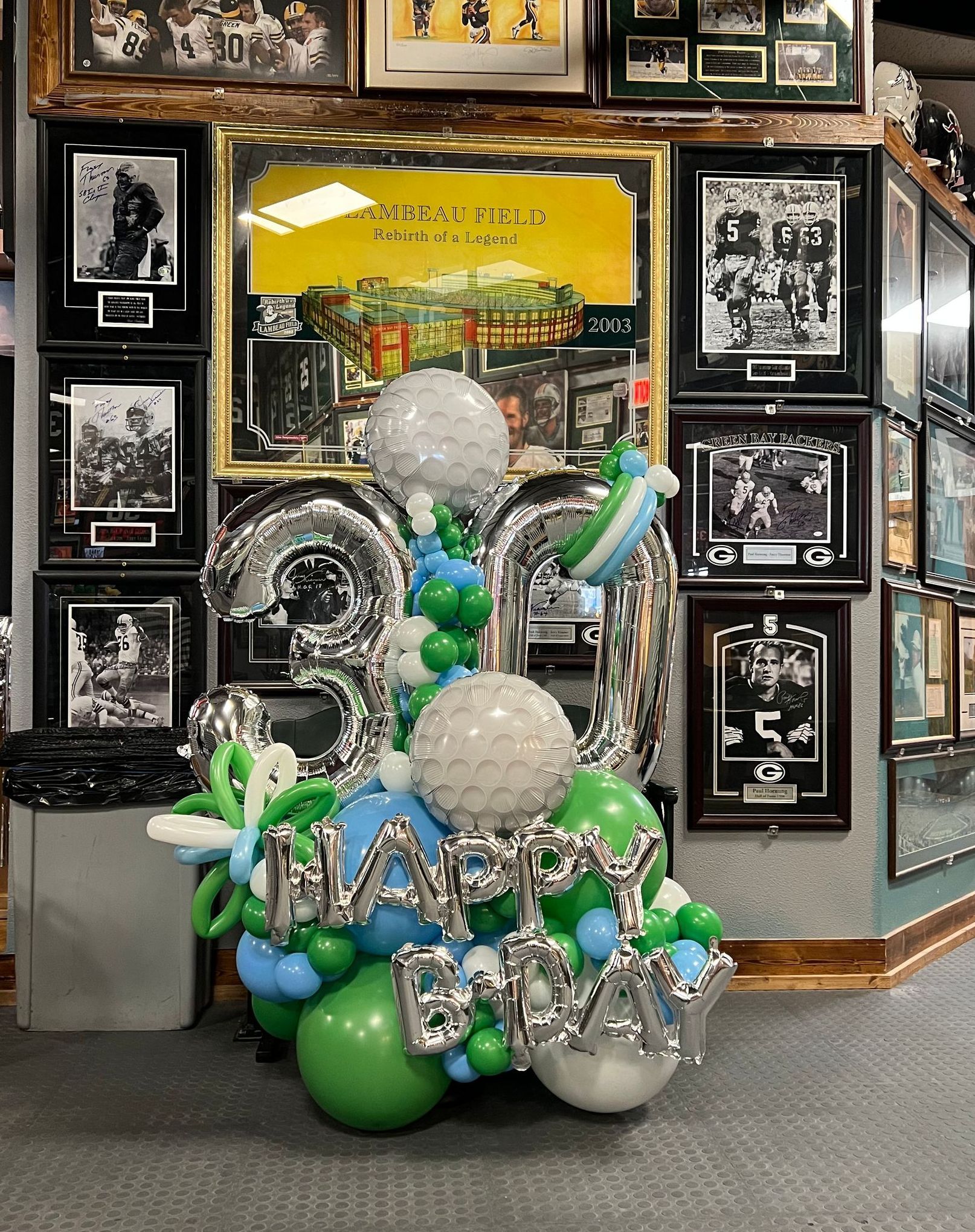 A bunch of balloons are sitting in front of a wall with pictures on it.