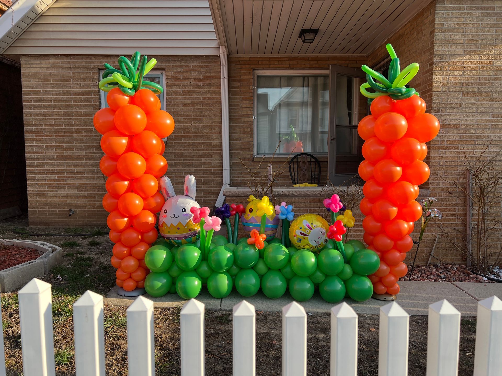 A house decorated with balloons in the shape of carrots and a bunny.