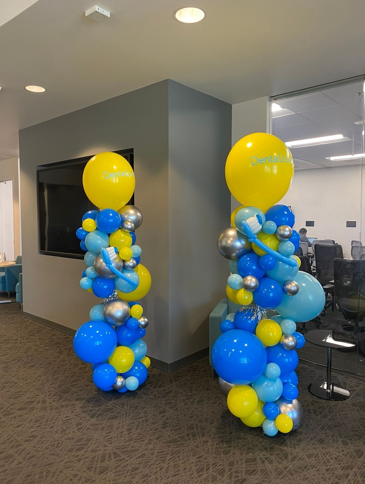 Two columns of blue and yellow balloons in a room.