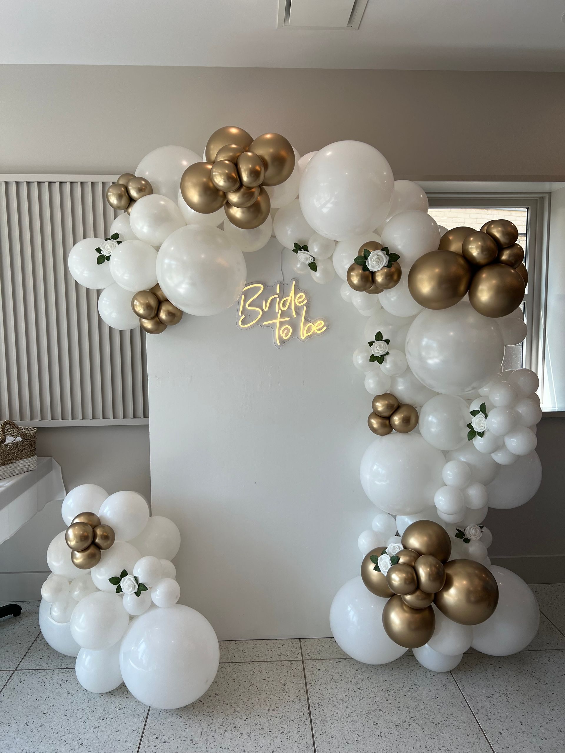 A castle made out of pink and gold balloons in a room.