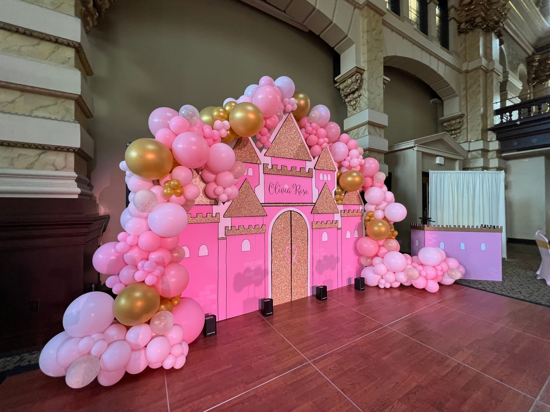A castle made out of pink and gold balloons in a room.