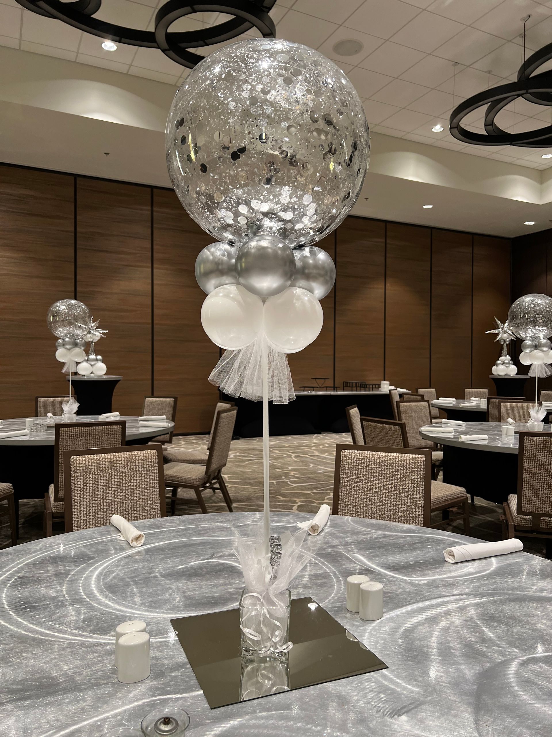 A table with a vase of flowers and balloons on it.