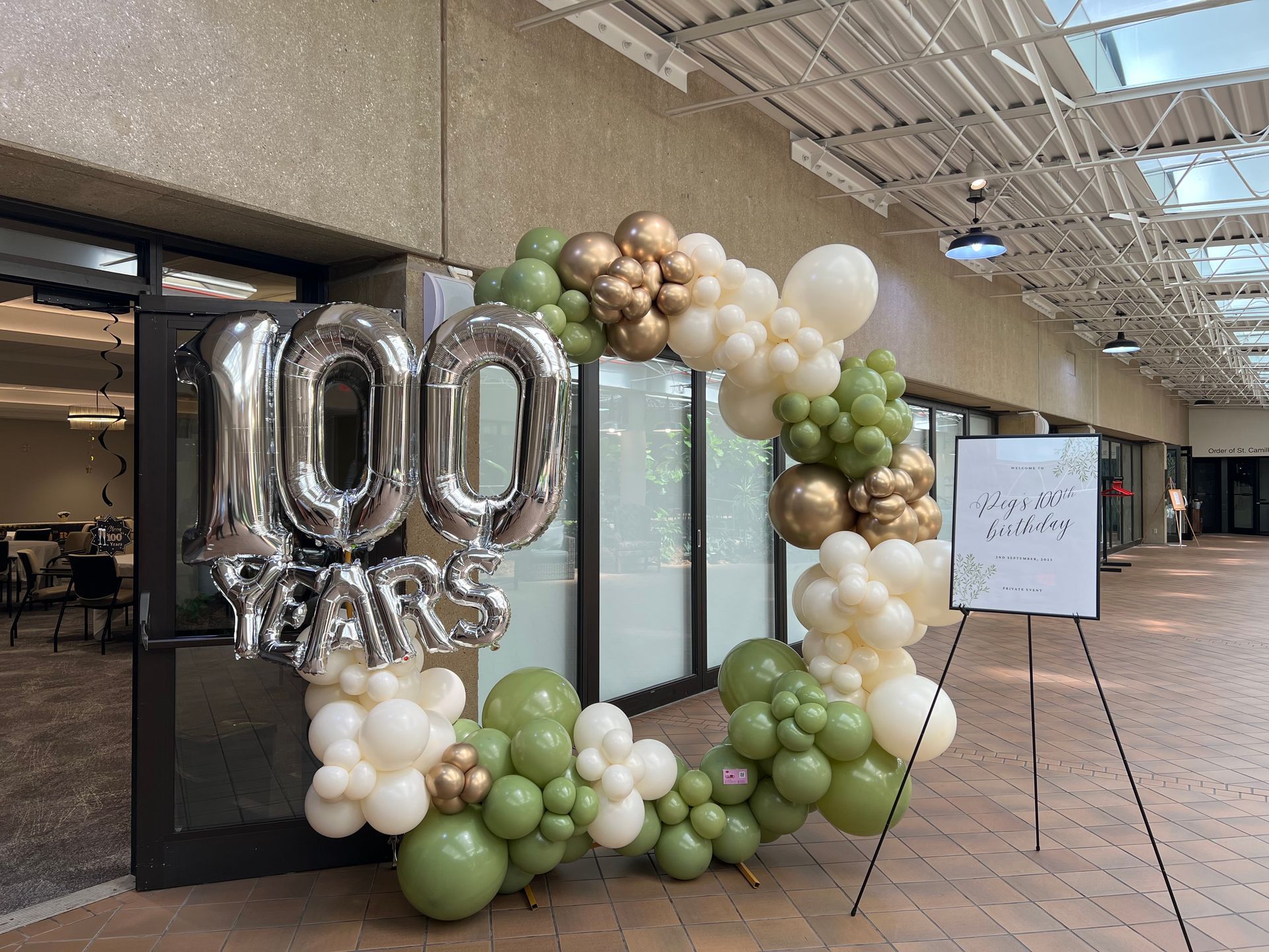 A balloon wreath with the number 100 on it is sitting in front of a building.
