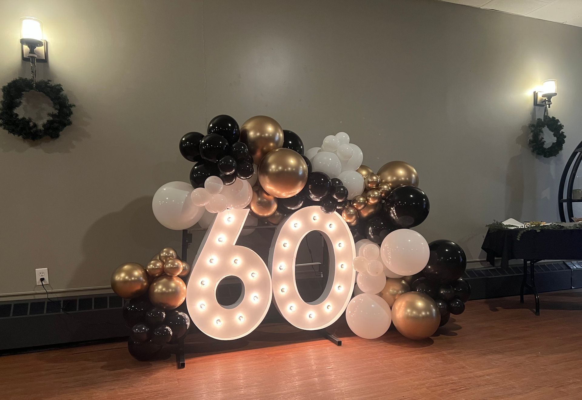 The number 60 is surrounded by balloons in a room.