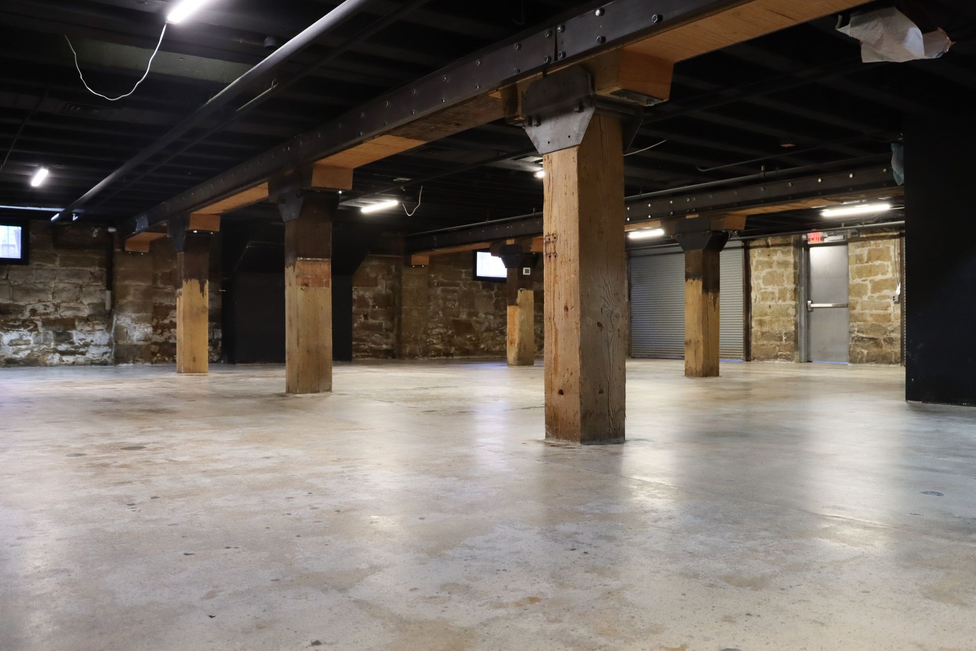 An empty basement with concrete floors and wooden pillars
