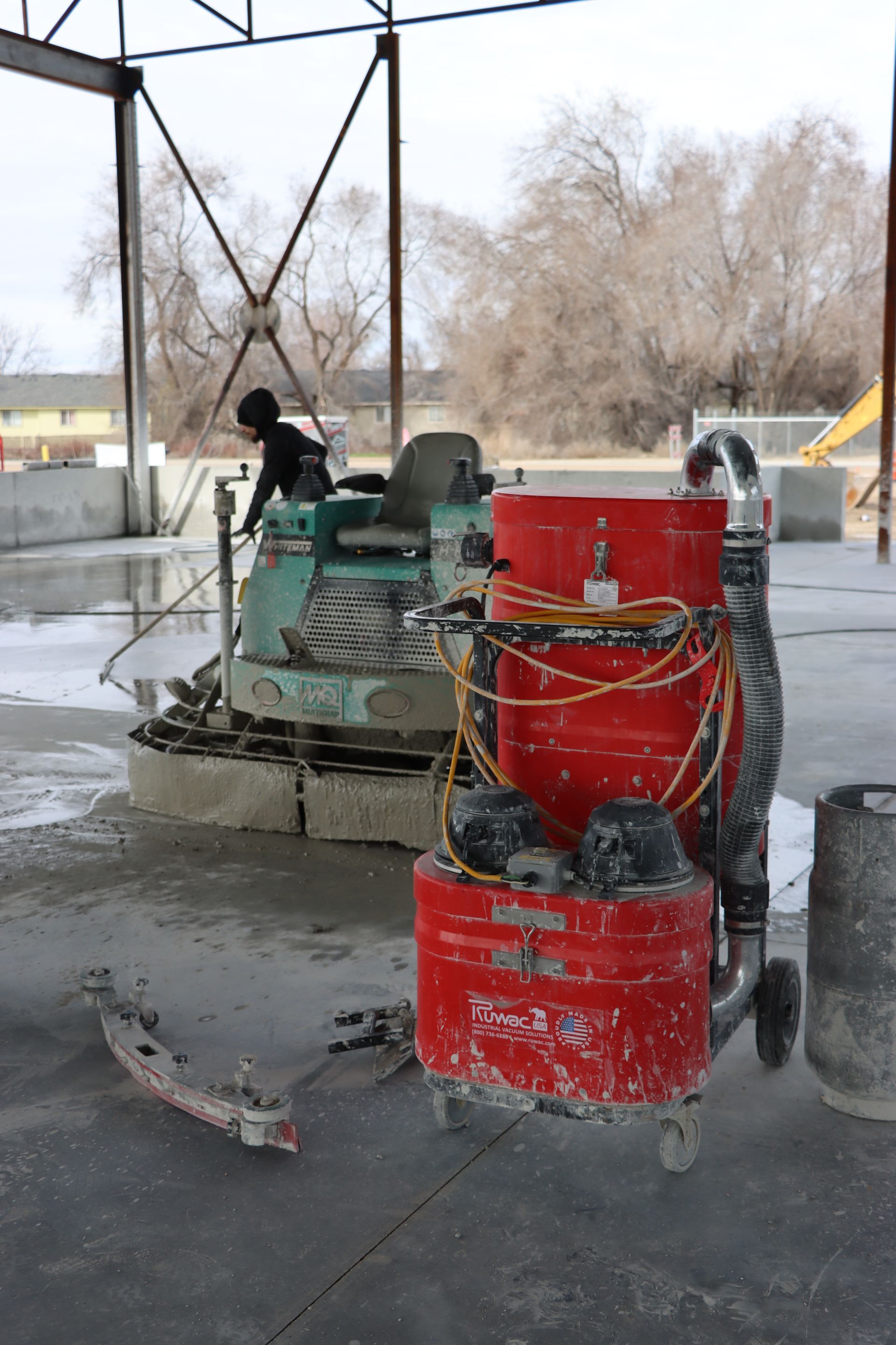 A vacuum cleaner is sitting next to a machine in a warehouse.