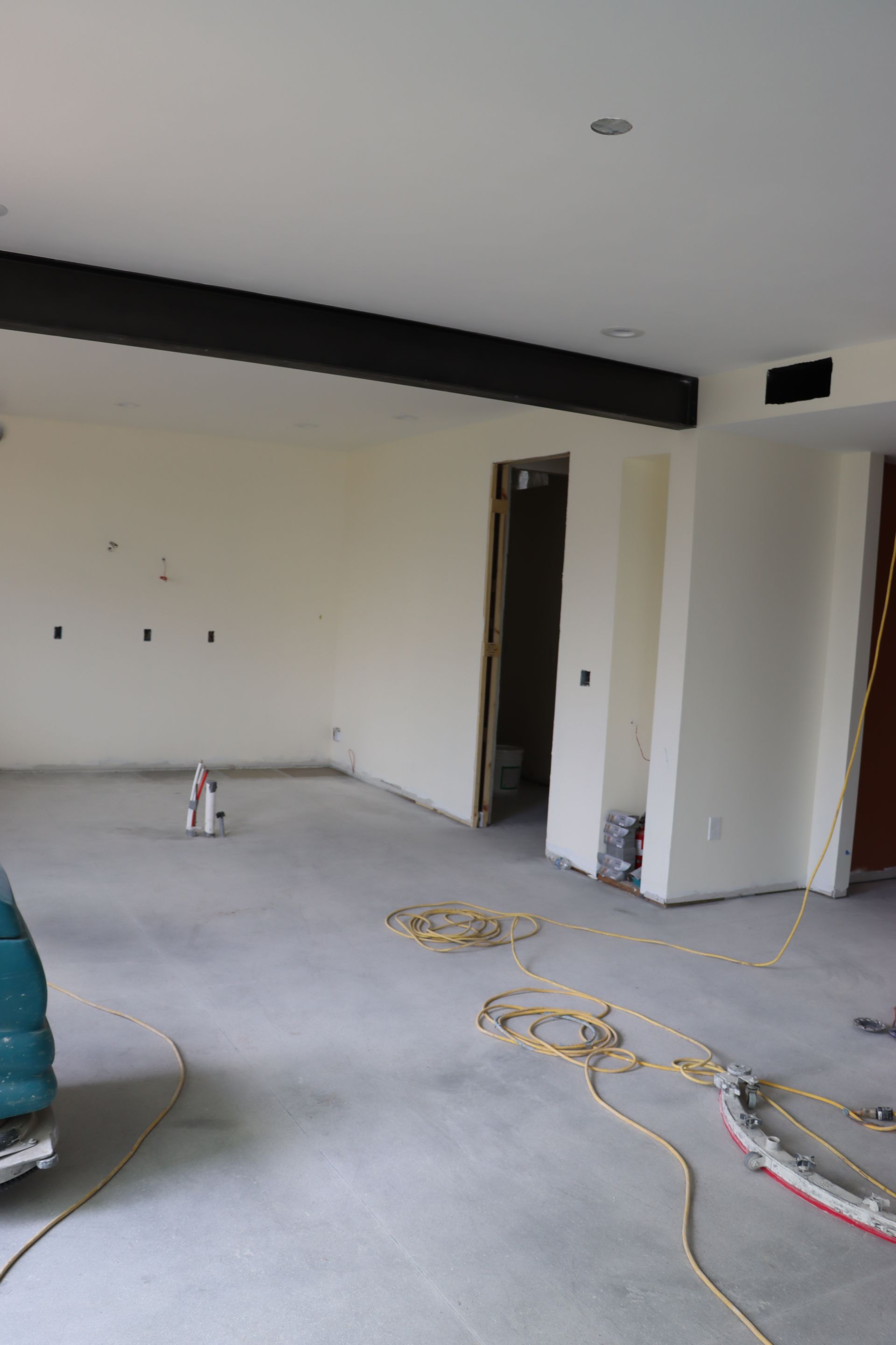 An empty room with white walls and a vacuum cleaner on the floor.