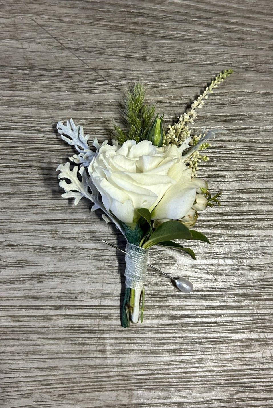 A white rose is sitting on top of a wooden table.