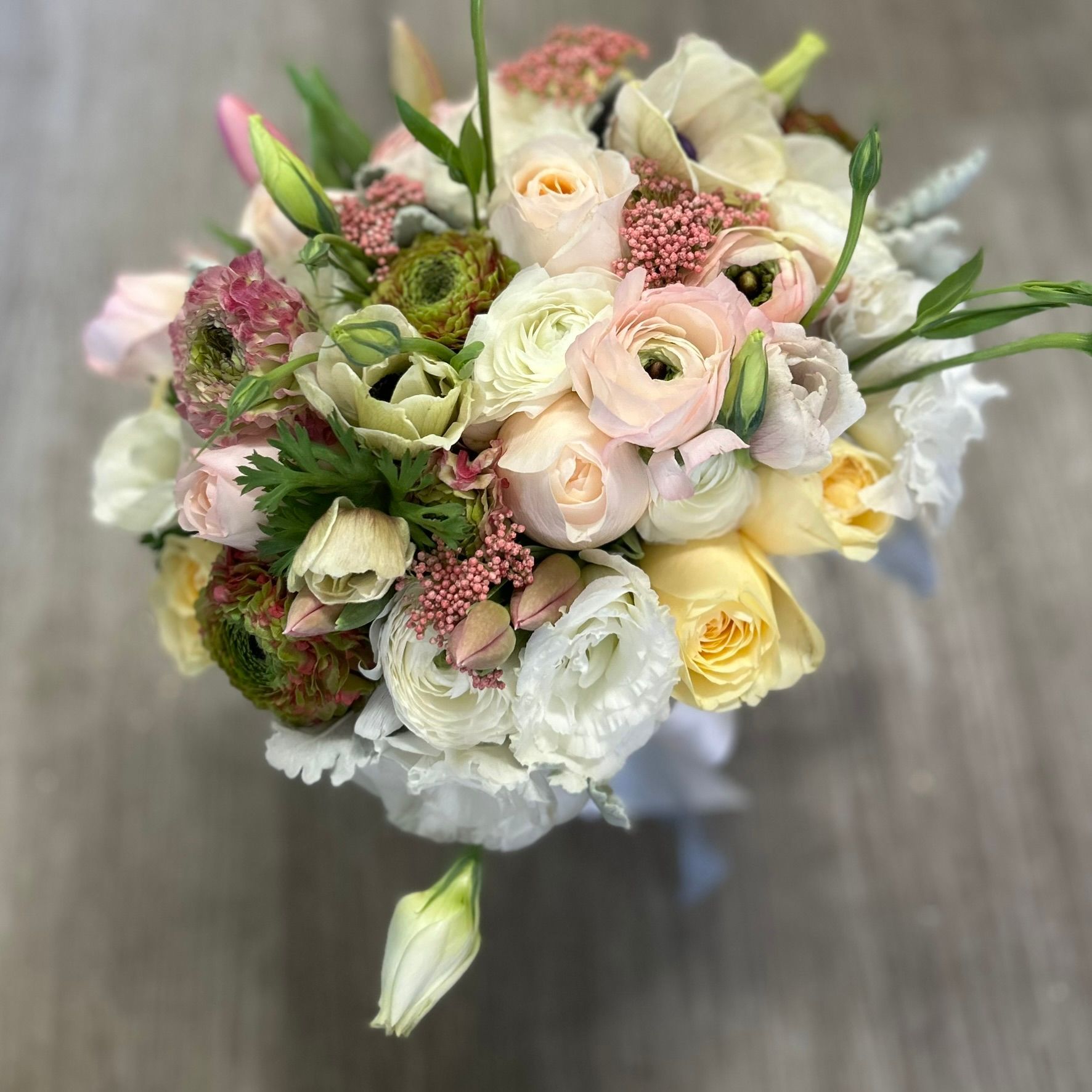 A pastel bridal bouquet with rununculus and grasses