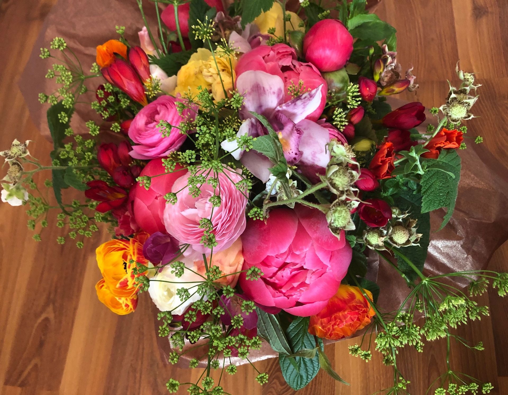 A bright and colorful bride's bouquet with peonies, ranunculus, freesia and raspberries.
