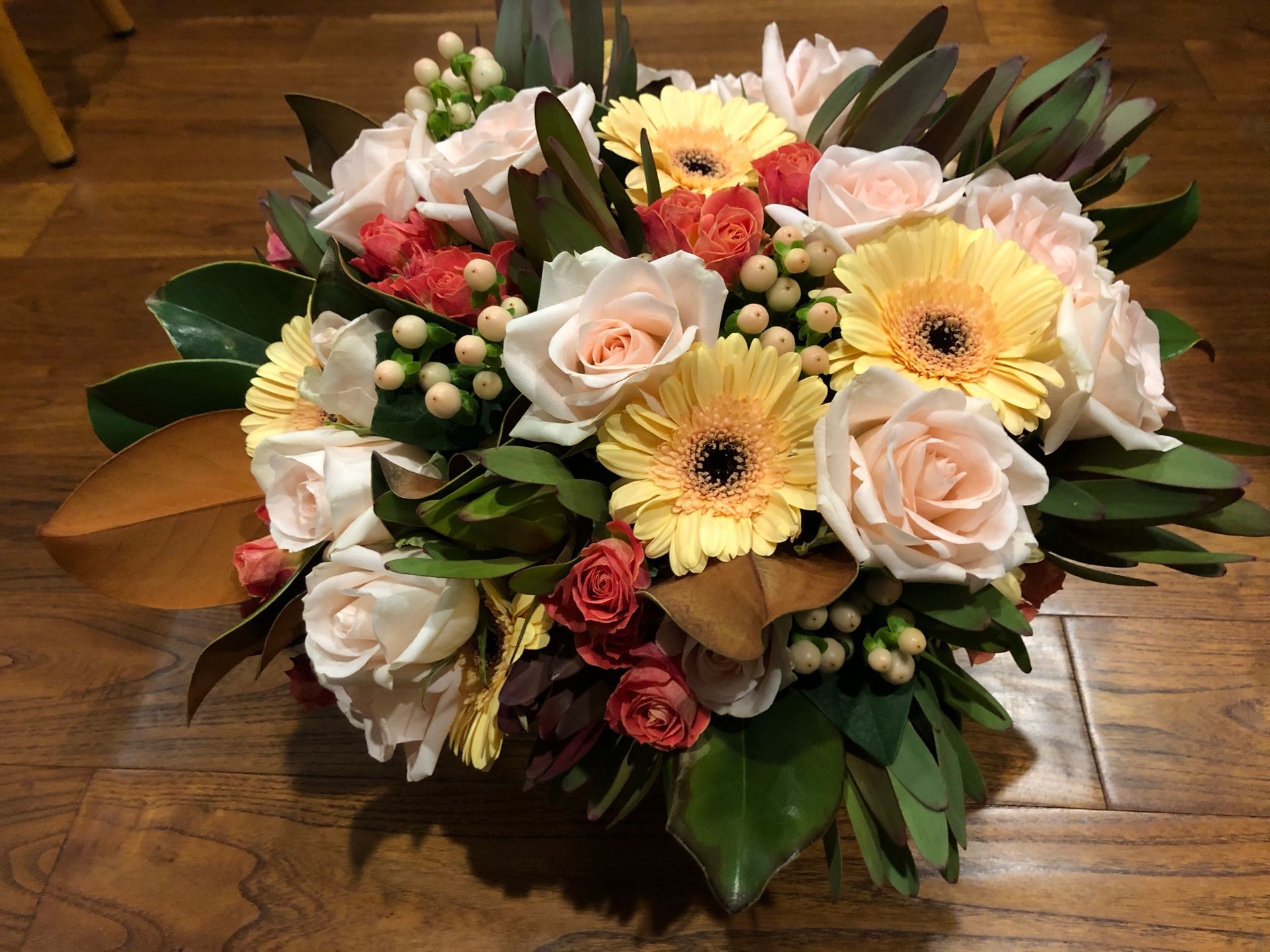 A bouquet of daisies and roses with berries 