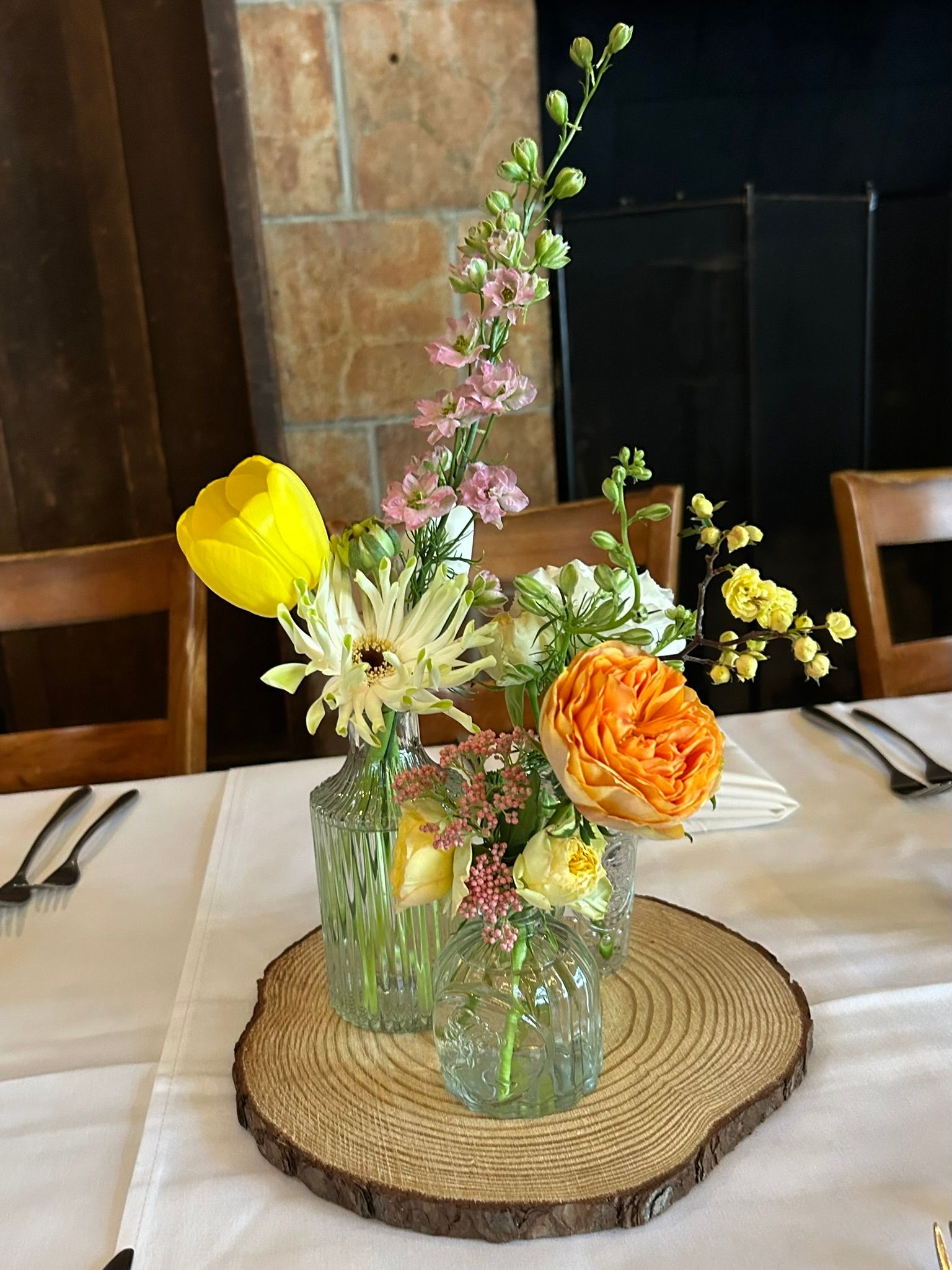A vase filled with flowers is sitting on a wooden slice on a table.