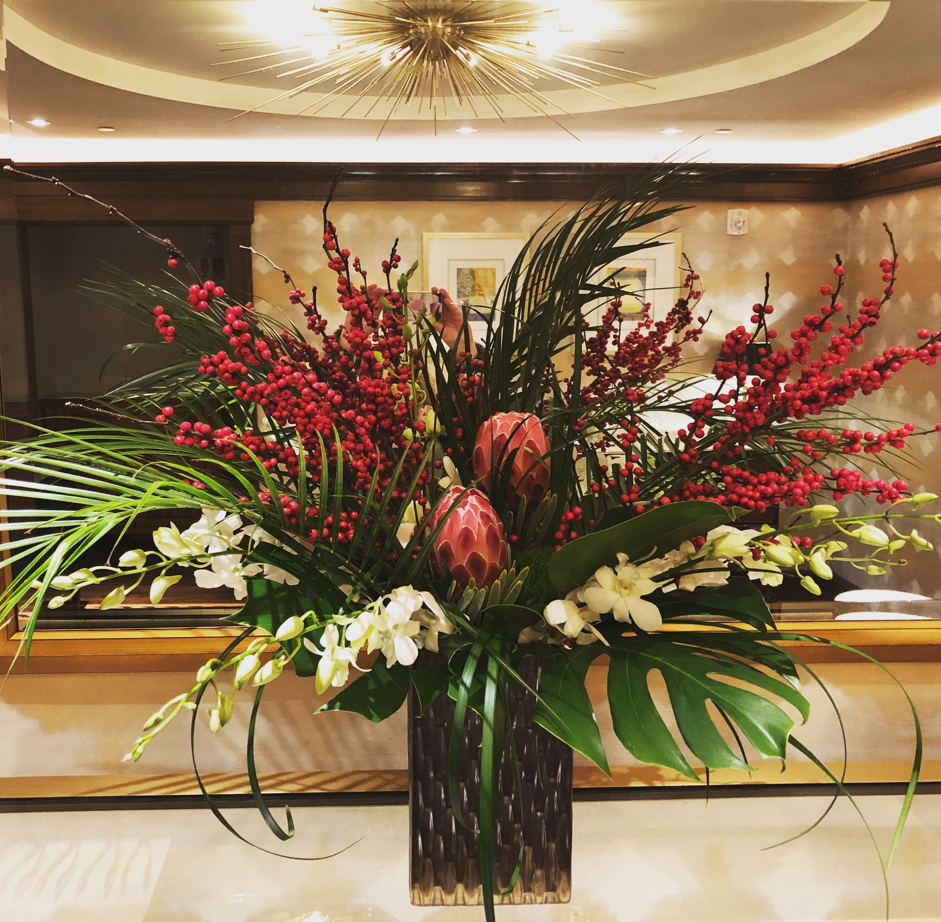 A modern striking winter flower design for a buffet made with Ilex and proteas