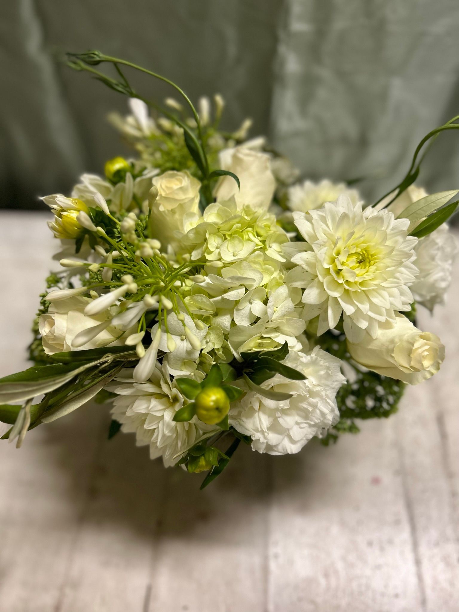 A bouquet of white flowers is sitting on a wooden table.