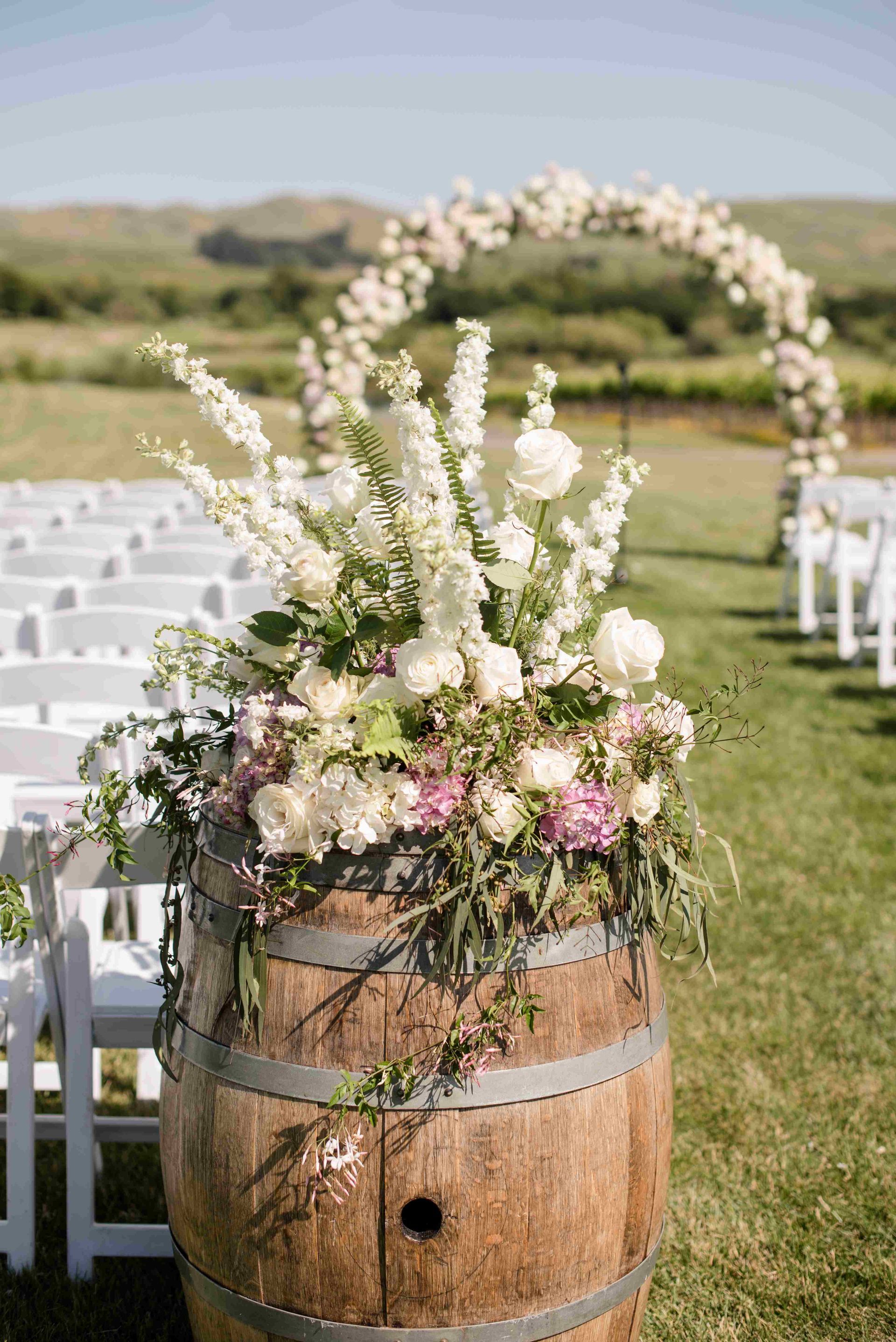 A wooden barrel cascading with flowers for a wedding aisle