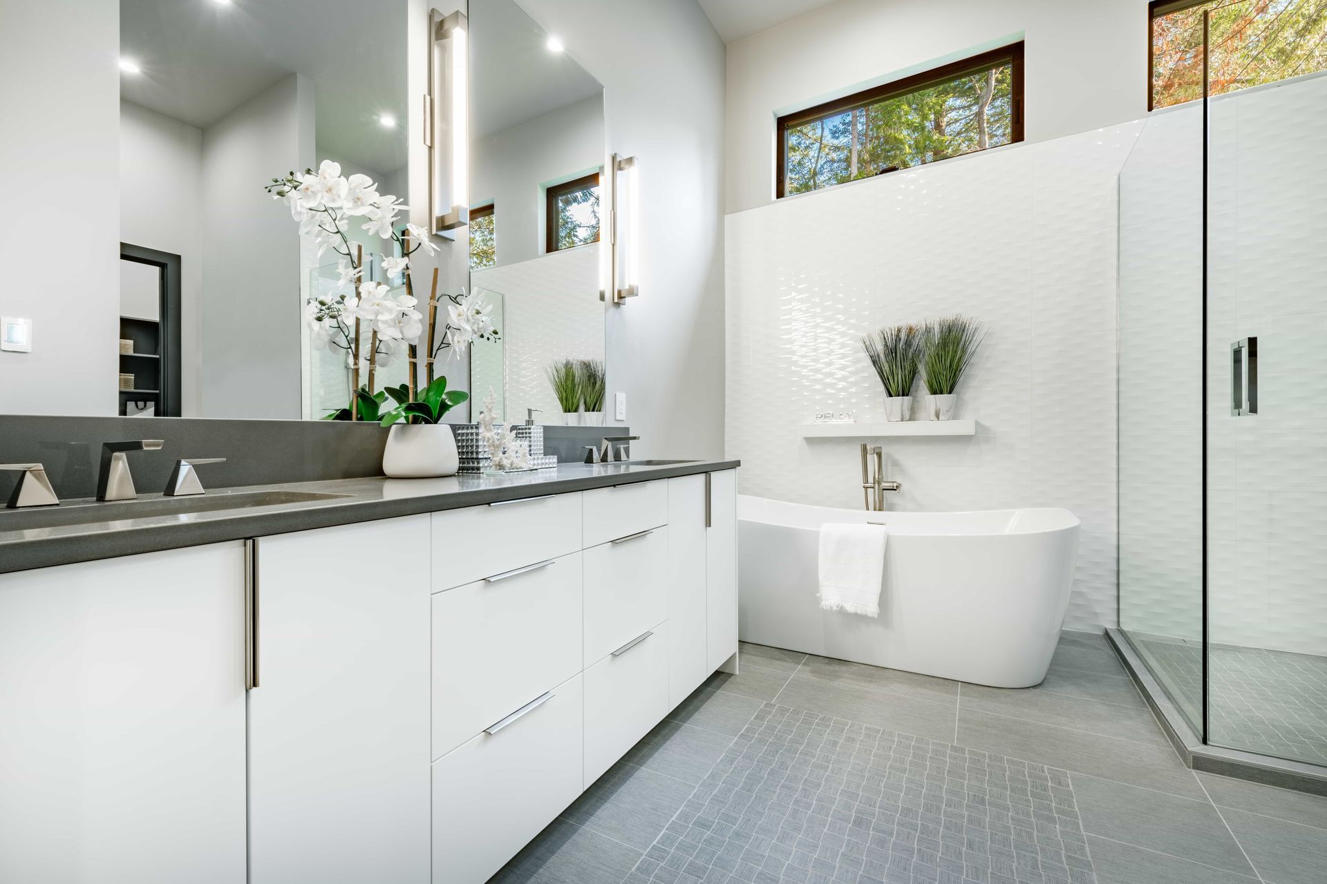 Modern white bathroom with a tub, shower, and double vanity with gray countertop.