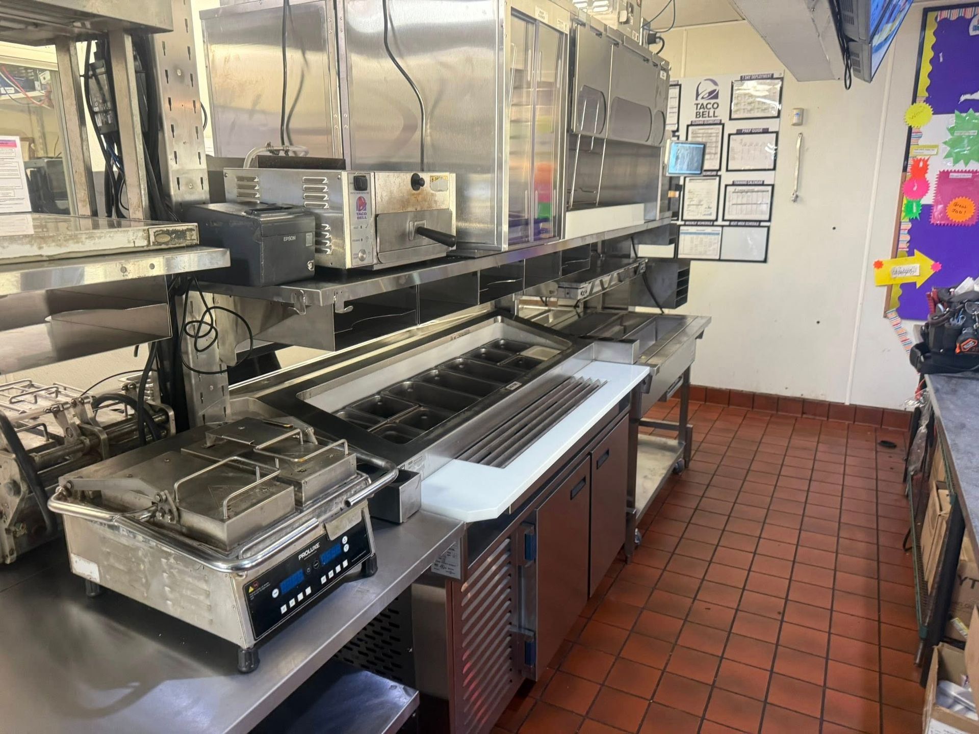 Restaurant kitchen with stainless steel equipment and tile flooring.