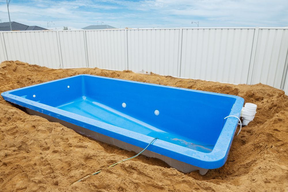 A Blue Swimming Pool Is Sitting In A Pile Of Sand — Arnway Pty Ltd In Kempsey, NSW