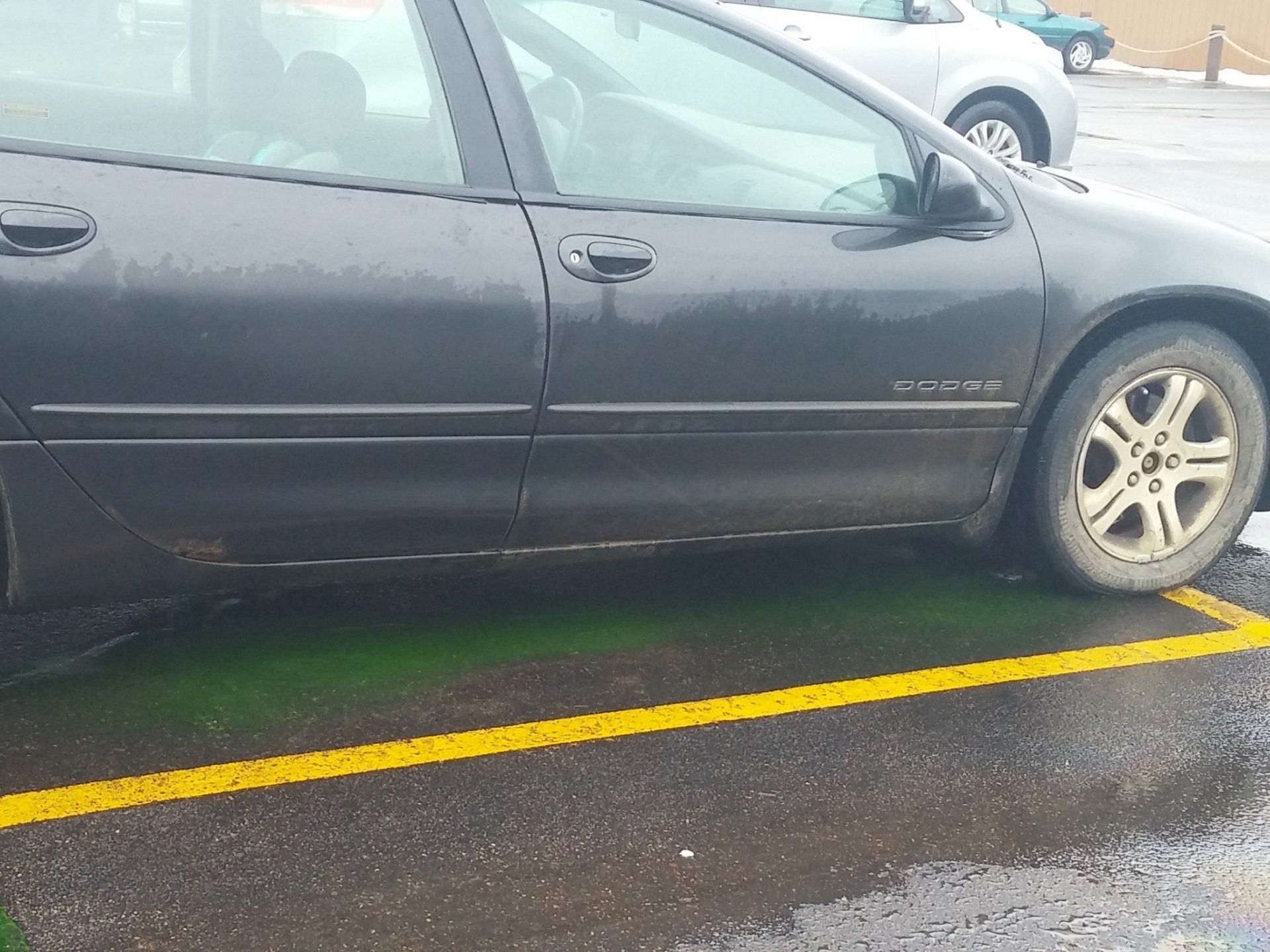 A black car is parked in a yellow line in a parking lot