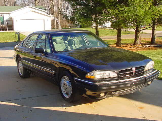 A black pontiac is parked in a driveway