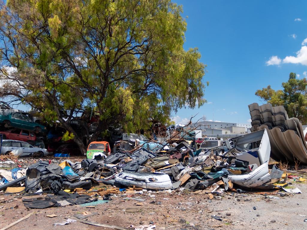A pile of junk in a parking lot with a tree in the background